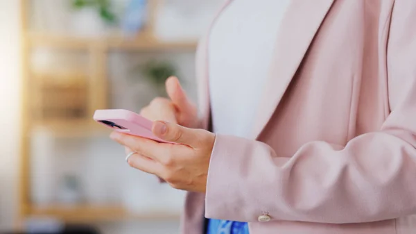 Business, woman and hands typing on smartphone in office, online app or contact technology. Closeup of female worker texting on pink cellphone for networking, notification and mobile media connection.
