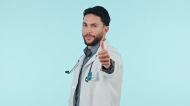 Adam, doktor ve baş parmak, sağlık desteği ya da başarı, teşekkürler ve mavi arka plandaki emoji gibi. Stüdyodaki hastane hizmetleri için evet, tamam ve iyi iş emojisi ile tıbbi çalışanın mutlu yüzü..