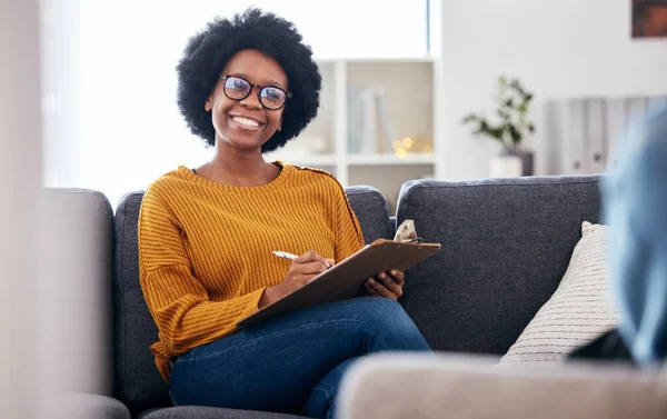 Black woman therapist on sofa with notes, smile and patient for advice and psychology, listening and mental health care help. Conversation, support and psychologist on couch with client in counseling.