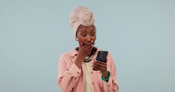 驚きと黒人女性 ソーシャルメディアのためのスタジオで携帯電話を持って ゴシップや灰色の背景に関するニュース Omg スマートフォン アフリカの女性モデル 秘密の絵文字 ドラマ または契約情報にサインアップ — ストック動画