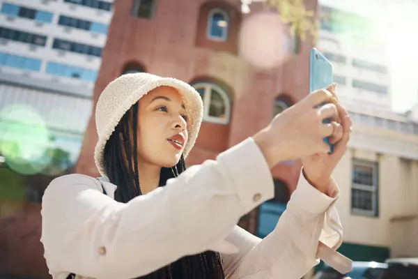 Woman on street with phone, live streaming in city and travel holiday blog for social media update. Influencer, streamer or gen z girl with urban fashion, smartphone and memory for content creation