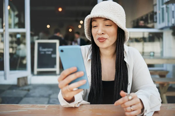 Student, travel and woman with phone at a cafe for social media, texting or chatting in a city. Smartphone, app and lady influencer at coffee shop for content creation, podcast or traveling blog post.