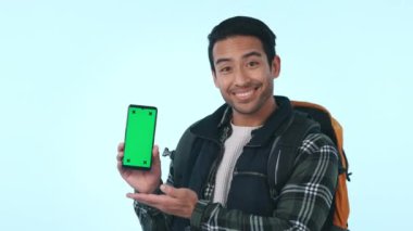 Mutlu Asyalı adam, telefon ve yeşil ekran. Sırt çantalı. Stüdyo arka planında model reklamlar var. Erkek ya da turist gösterisi Tamam, evet işareti gibi mükemmel cep telefonu uygulaması ya da görüntüleme.