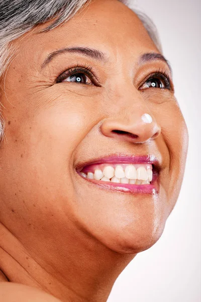 Cream, face and thinking with a mature woman with glow and smile on a white background. Dermatology, moisturizer and cosmetics zoom of aesthetic model for facial shine, beauty or skin care in studio.