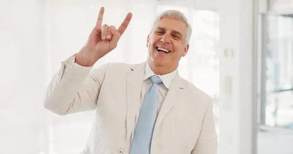 Portrait, rock hand gesture and a senior businessman in the office with a smile for motivation or success. Management, leadership and a happy CEO in the workplace with freedom, energy or horns emoji.