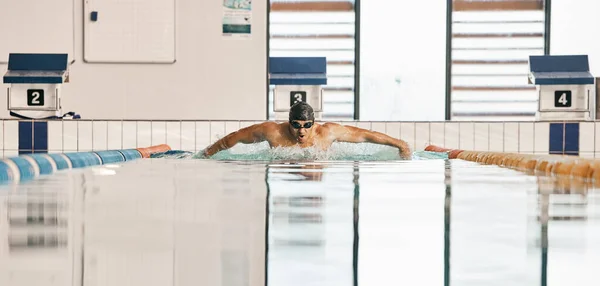 Swimming exercise, pool and sports man doing water challenge, cardio training or butterfly stroke action. Motivation, athlete and swimmer workout, practice or training for competition, match or race.