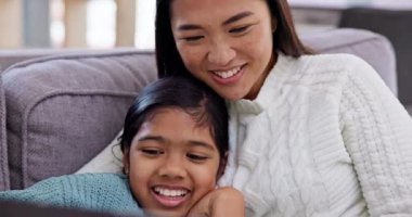 Anne, çocuğuyla birlikte oturma odasında dizüstü bilgisayarla kanepede film izliyor. Mutlu, kaynaşmış ve Asyalı bir anne evinde bilgisayar başında film ya da şov izleyip kız çocuğu kucaklıyor.