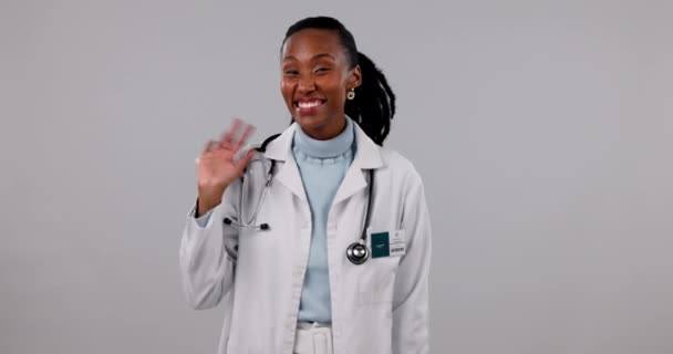 病院スタジオ 黒人女性 医療挨拶 医療歓迎 ウェルネスサポートのための医師の波 クリニックの肖像画 こんにちはジェスチャーやアフリカの専門家 外科医やグレーの背景に看護師 — ストック動画