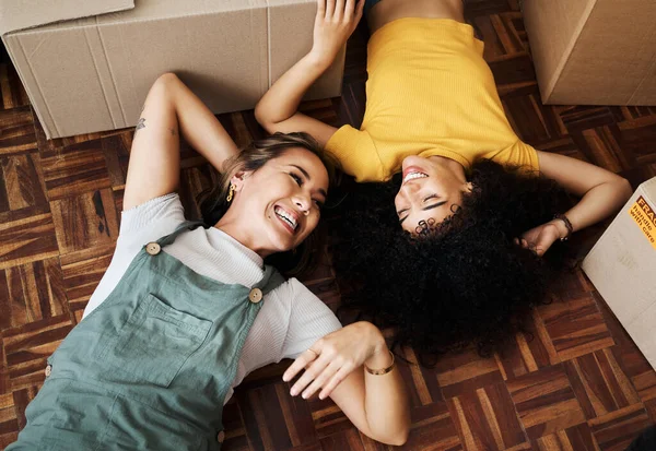 Top view, lesbian and couple on the floor, boxes and funny with love, bonding and homeowners. Queer people, lgbtq and women on the ground, new apartment and property with achievement and real estate.