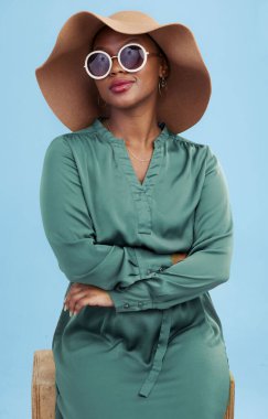 Moda, güneş gözlüğü ve yaz için havalı bir tarzı olan siyah kadın portresi stüdyonun mavi arka planında izole edilmiş. Afrikalı, şapkalı ve genç insanlar cazibe veya lüks aksesuarlar için giysileriyle seyahat ederler..