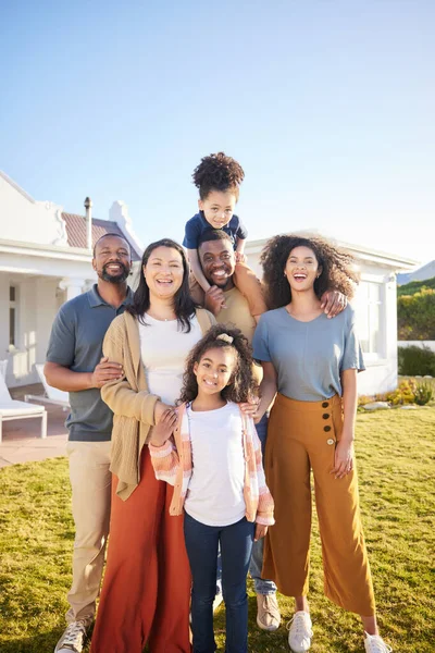 Children, parents and grandparents at house outdoor to relax for summer vacation. Men, women and kids or interracial family portrait together at holiday home or real estate property with sky banner.