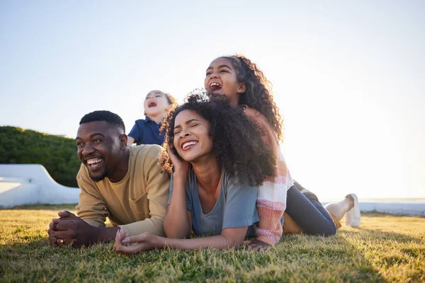 Grass, funny and family relax on vacation, bonding and having fun together on mockup space. Children, laughing and interracial parents in nature to travel on holiday, care and love outdoor at garden.