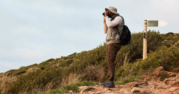 Hiker, binocular or black man on mountain in nature on trekking journey or adventure for fitness. Hiking, holiday vacation or African person walking to search in park for exercise or view on hill.