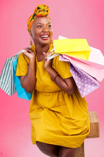 Shopping, thinking and black woman with bags, luxury items and fashion on a pink studio background. African person, customer or model with expensive clothes, retail or boutique products with decision.