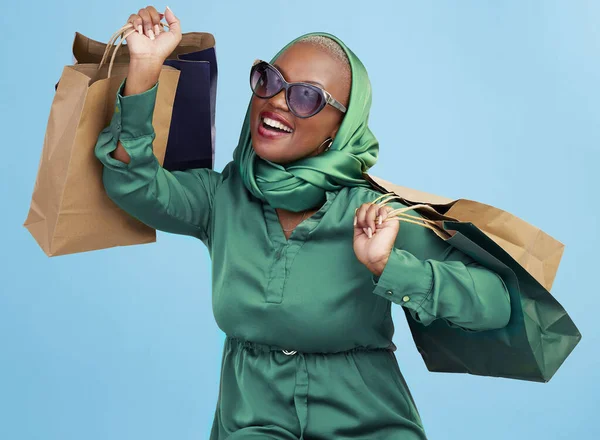 Shopping bag, studio smile and black woman excited for luxury fashion spree, mall store sales or commerce deal. Retail therapy package, market gift choice and rich African customer on blue background.