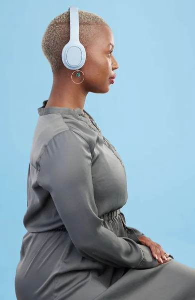 Headphones, music and profile of black woman on blue background for wellness podcast, relax and chill. Profile, technology and African person streaming audio, listening to radio and song in studio.