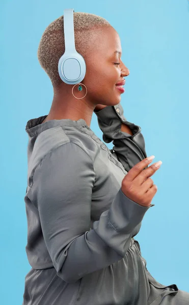 Black woman, headphones and music, profile and technology with audio streaming isolated on blue background. Listening to radio, wireless tech for podcast and subscription with peace in studio.