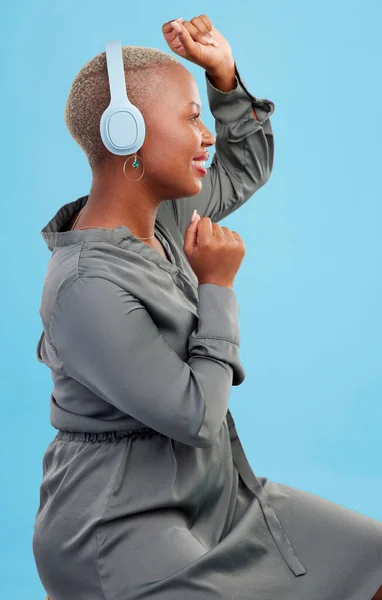 Black woman, headphones and dancing in studio profile, happy and listening by blue background. African dancer girl, smile and streaming subscription for sound, audio tech and hearing for celebration.