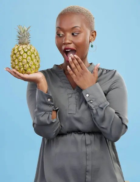 Pineapple, wow and surprise with a health black woman in studio on blue background for diet or nutrition. Wellness, fruit or food with a young person looking shocked by vitamins or minerals benefits.
