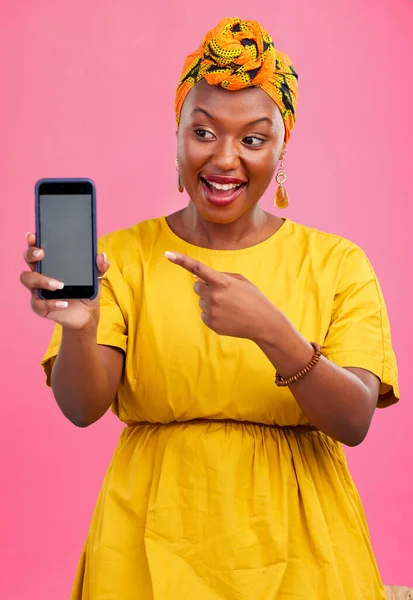 Happy black woman, phone and pointing to mockup space in advertising against a studio pink background. African female person smile showing technology app, display or screen for deal, discount or sale.