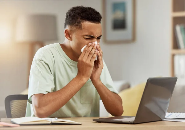 Sneeze, man and tissue in living room with flu, virus or cough while learning online at home. Health, person and fever blow nose with tissue from influenza, illness or cold by table in apartment.