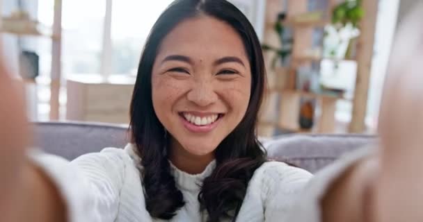 セルフィー 幸せなアジアの女性は ビデオを録画するために彼女のアパートのリビングルームのソファーに閉じ込められています ソーシャルメディアのホームムービーを撮影する自信のあるインフルエンサーの肖像画 — ストック動画