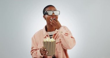Üç boyutlu, gözlüklü ve komik film için patlamış mısırlı siyahi bir kadın. Ve stüdyoda yüksek teknolojili sinema yemekleri. Komedi, mısır atıştırmalığı ve beyaz arka planda dijital dünyası ve videosu olan tiyatro..