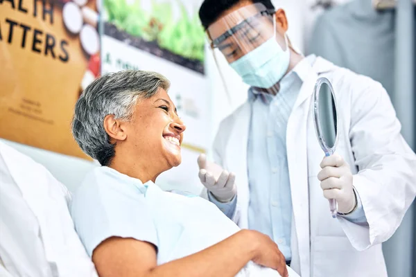 Dentist in mask, patient with smile and mirror for healthcare, cleaning and hygiene for teeth. Happy woman in chair, dental care technician and safety in surgery on mouth, professional doctors office.