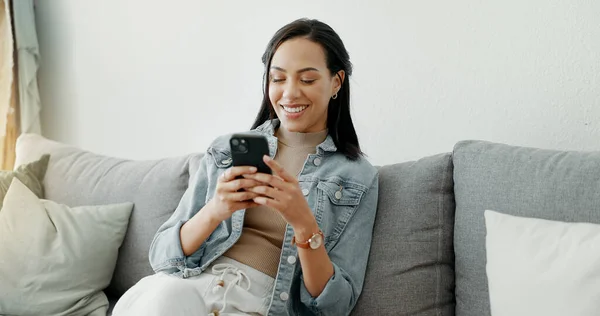 Woman, relax and typing on smartphone on sofa, reading social media post or mobile chat at home. Cellphone, app and download digital games, scroll connection or multimedia notification in living room.