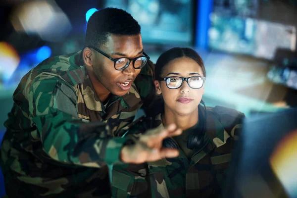 Night surveillance, army and people with a computer for communication, planning strategy or teamwork. Cyber security, data center and a black man talking to a woman about monitor in a military room.