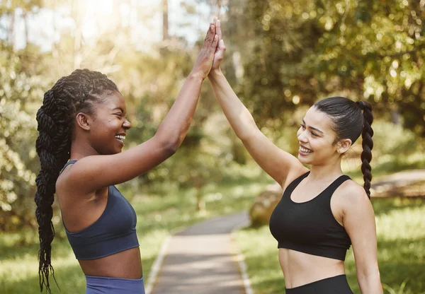 Woman, friends and high five in nature for fitness, teamwork or outdoor training goals together. Female person touching hands in celebration for team exercise, running or sports practice at the park.