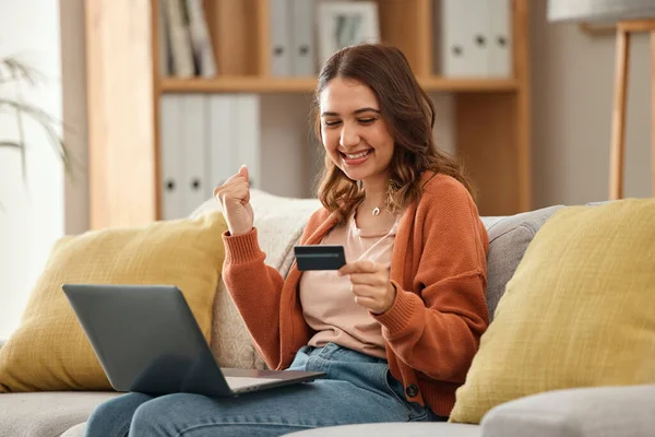 Excited, woman and laptop with credit card, banking and online shopping with fintech, transaction and happiness in a lounge. Person, home and girl on a couch, pc and celebration with payment or bonus.