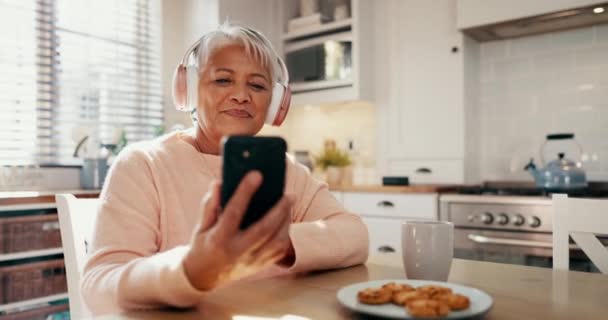 手机和在厨房里听音乐 听专辑或听音乐的老年妇女 年长的女性在家里的社交媒体或互联网上唱歌 阅读博客 — 图库视频影像