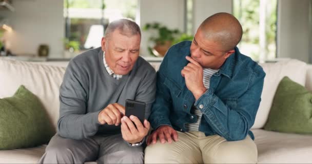 年长的父亲 在家里的沙发上与电话交谈 帮助社交媒体 网络或聊天 老年人和他的儿子在客厅里用智能手机在网络应用上交谈 — 图库视频影像
