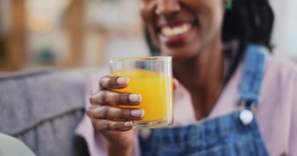健康的な食事 ウェルネスでソファーの家のリビングルームでハッピー 黒人女性とオレンジジュース アフリカの人 笑顔と水分補給でフルーツガラスを飲む 有機ビタミンCやビーガンの利点 — ストック動画
