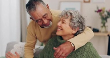 Mutlu, kucaklaşan ve evdeki kanepede oturan ırklar arası yaşlı çift ve sevgi ve özenle emeklilik. Ev, oturma odası ve dinlenme odasındaki yaşlı insanlar kucaklaşmalı ve gülümsemeli romantizm..