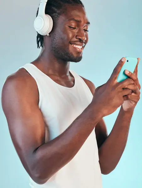 スマートフォン ヘッドフォン 黒人の男性が音楽を聴き オーディオストリーミングで微笑み 青い背景で孤立したチャット サウンド モバイルアプリ ポッドキャスト ラジオ スタジオでの接続 — ストック写真