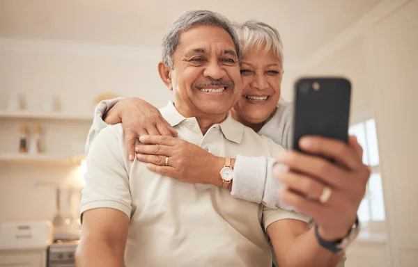 Senior couple, home and smile with smartphone for video call, mobile streaming and scroll on social media in retirement. Happy old man, woman and hug with phone for selfie, reading news app and relax.
