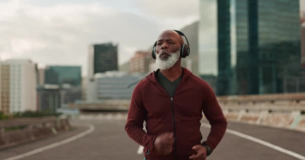 市内のシニアマン ランニング ヘッドフォン ストリート フィットネス ウェルネスのビジョン 高齢のアフリカ人ランナー 都市道路 ケープタウンでインスピレーションを得た音楽によるトレーニング — ストック動画