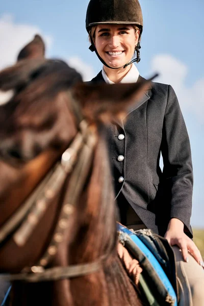 Portrait, equestrian and a woman with an animal on a ranch for sports, training or a leisure hobby. Horse riding, smile or competition and a happy young rider in uniform with her stallion outdoor.