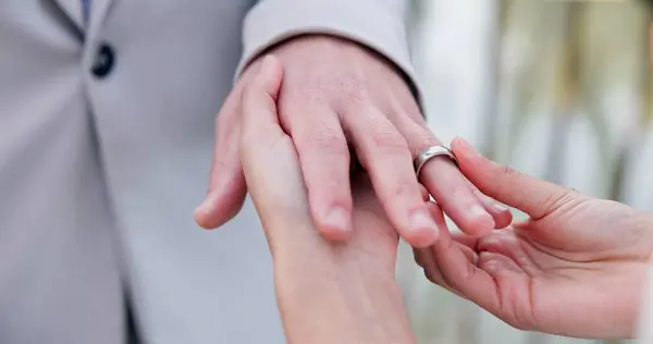 Couple, holding hands and ring for marriage, wedding or ceremony for commitment, love or support. Closeup of people getting married, vows or accessory for symbol of bond, relationship or partnership.