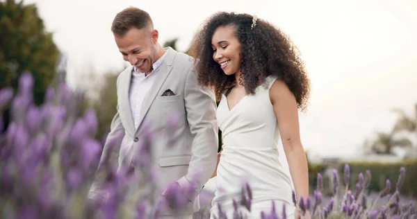 Wedding, bride and groom holding hands in meadow, celebrate love with happiness and commitment. Marriage, trust and people in interracial relationship, event and nature with love and care outdoor.