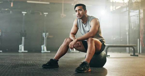 Fitness, breathing and sweating with a tired man in the gym, resting after an intense workout. Exercise, health and fatigue with a young athlete in recovery from training for sports or wellness.