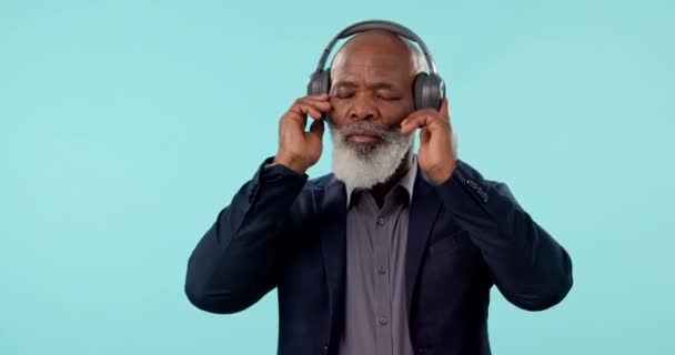 年长的黑人男人 带着耳机和音乐 带着蓝色背景的精力和健康地跳舞 在演播室使用无线技术的无线电 音频和老板 在狂欢作乐中自由和跳舞 — 图库视频影像