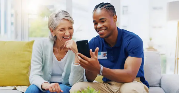 Phone, medical and a nurse talking to a patient in an assisted living facility for senior people. Healthcare, mobile and contact with a black man medicine professional chatting to a mature woman.