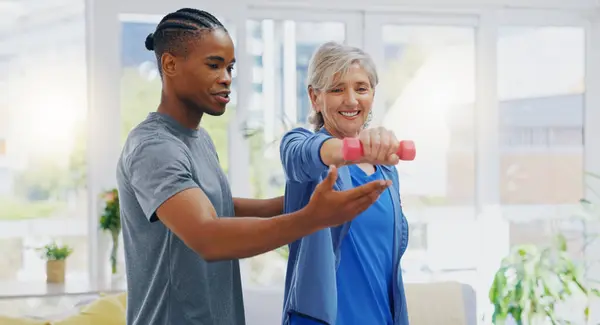 Elderly woman, dumbbells and rehabilitation therapist for exercise in a nursing home. Happy senior patient with physiotherapist man or nurse for healing, health and physiotherapy for muscle and body.
