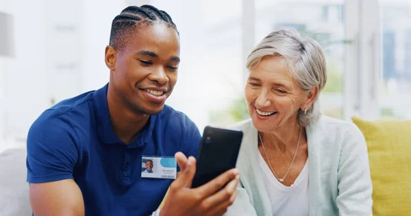Phone, medical and a nurse talking to a patient in an assisted living facility for senior people. Healthcare, mobile and contact with a black man medicine professional chatting to a mature woman.