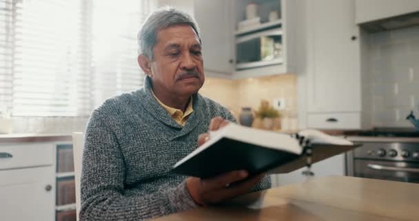 Senior Mann Lesen Und Bibelstudium Der Heimischen Küche Für Spirituelles — Stockvideo