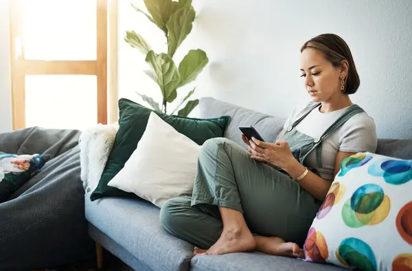 stock image Woman, relax on sofa with smartphone and chat online with communication, wellness and reading text message. Email, technology and mobile app with virtual conversation, typing on social media at home.