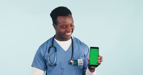 快乐的男人展示手机和绿色屏幕在工作室远程保健 在线保健和专家建议 医疗专业人员 护理人员或拥有蓝色背景健康数字应用程序的医生 — 图库视频影像